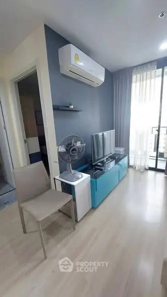 Modern living room with air conditioning, TV, and balcony access in a stylish apartment.