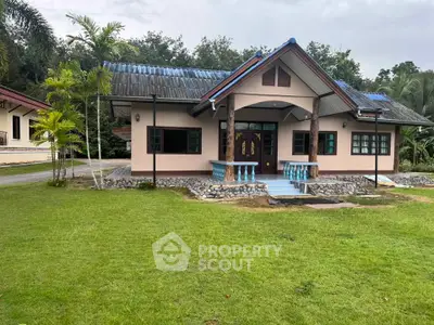 Charming single-story house with lush green lawn and tropical surroundings.