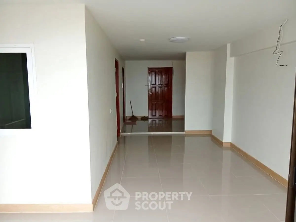 Spacious unfurnished apartment interior with tiled flooring and wooden accents, ready for customization.