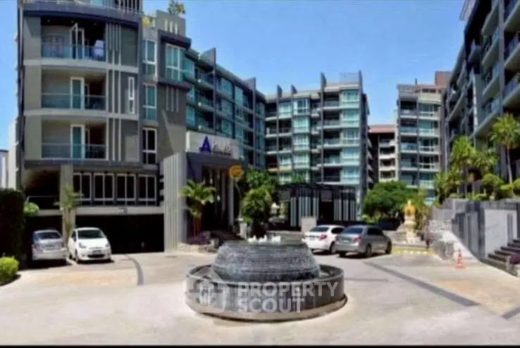 Modern apartment complex with fountain and parking area, showcasing contemporary architecture.