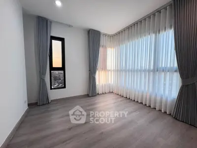 Spacious corner unit with large windows and elegant curtains, offering abundant natural light and modern flooring.