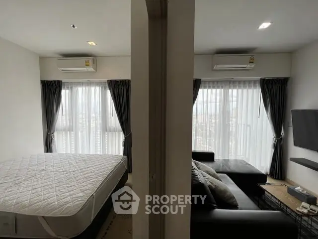 Modern apartment with bedroom and living room, featuring large windows and air conditioning.