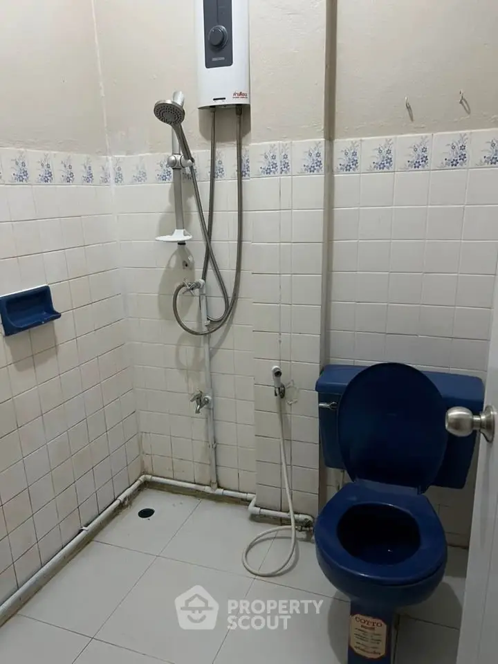 Compact bathroom with shower and blue toilet seat, ideal for efficient space use.