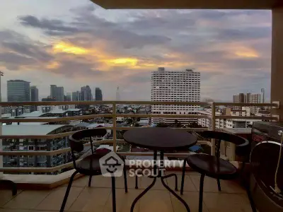Stunning balcony view of city skyline at sunset with cozy seating area.