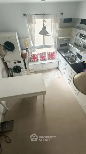 Charming kitchen with modern appliances and cozy seating area, featuring a washing machine and stylish decor.