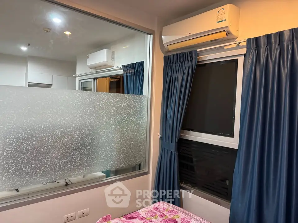 Cozy bedroom with air conditioning and large window, featuring elegant blue curtains and floral bedding.