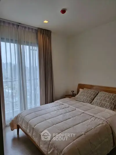 Cozy bedroom with large window and modern decor in a high-rise apartment.