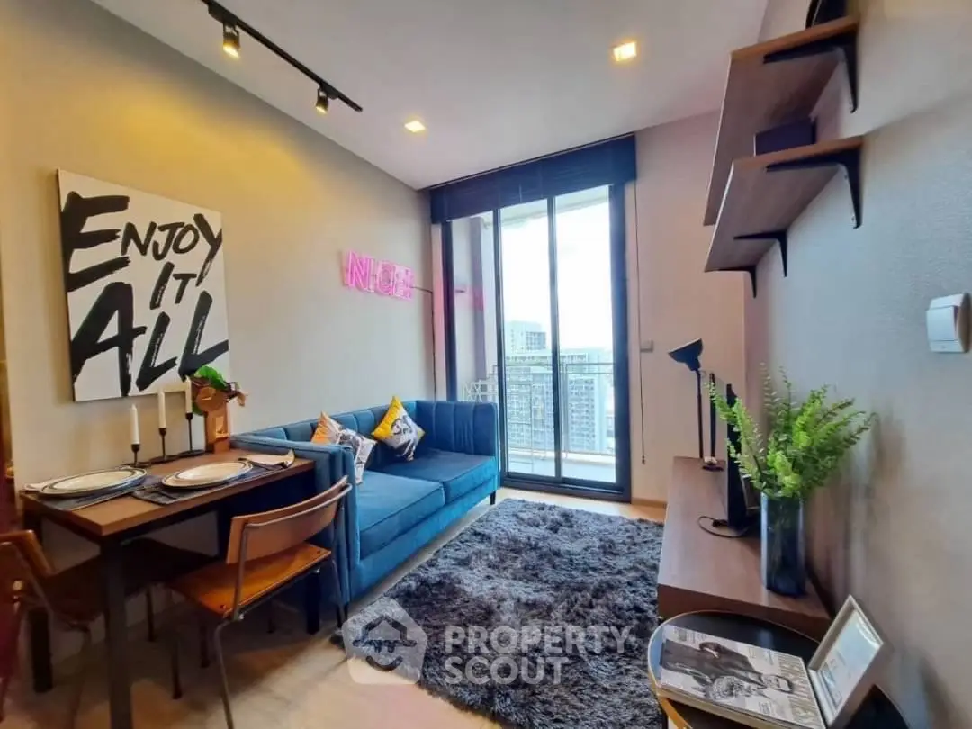Stylish modern living room with balcony view, cozy decor, and vibrant wall art in urban apartment.