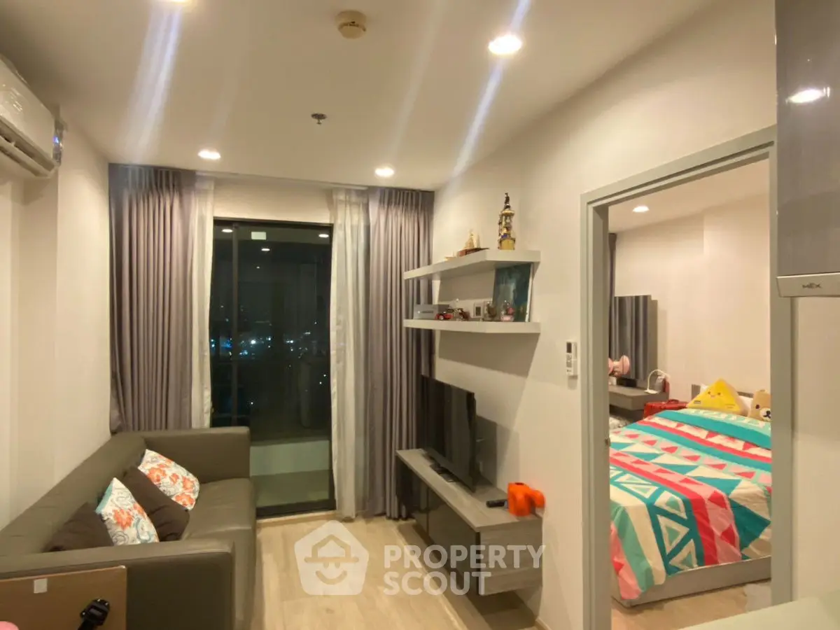 Modern living room with cozy sofa and TV, adjacent to a colorful bedroom.