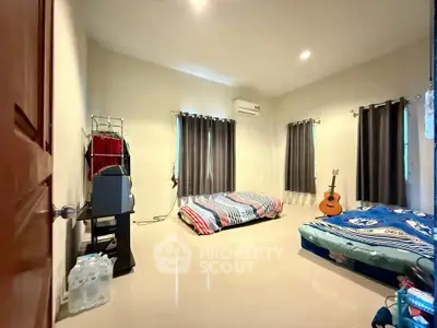 Spacious bedroom with twin beds and natural light, perfect for relaxation and comfort.