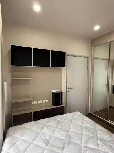 Modern bedroom with sleek storage and mirrored closet doors, perfect for urban living.