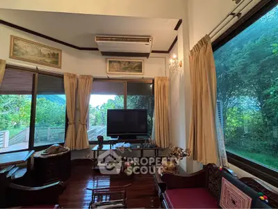 Charming living room with large windows and lush garden view, featuring elegant decor and cozy seating area.