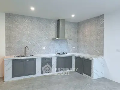 Modern kitchen with sleek gray cabinets and marble countertops in a stylish open layout.