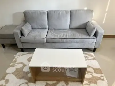 Modern living room with stylish gray sofa and chic coffee table on patterned rug.