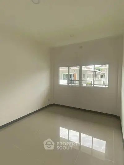 Bright empty room with large window and tiled floor, ideal for customization.