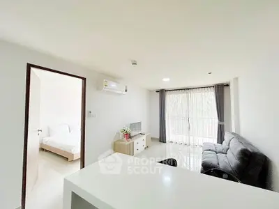 Bright modern living room with sleek furniture and large window, adjacent to a cozy bedroom.