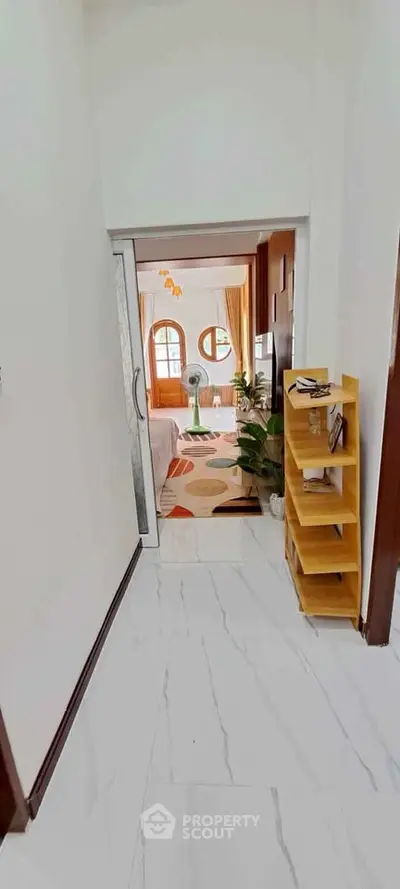 Charming hallway leading to a cozy living room with stylish decor and natural light.