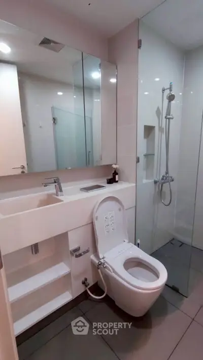 Modern bathroom with sleek fixtures and glass shower enclosure in a contemporary apartment.