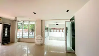 Spacious modern living room with large windows and ceiling fans, offering abundant natural light.