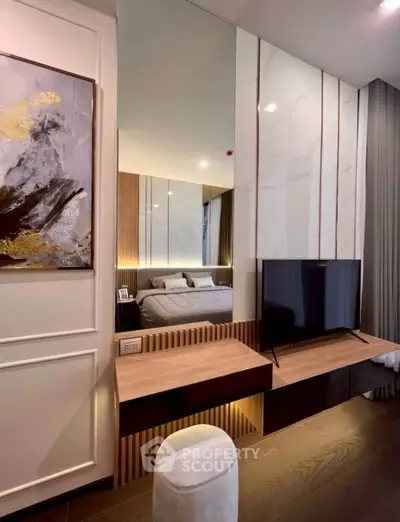 Modern bedroom with stylish decor and mounted TV, featuring elegant lighting and contemporary artwork.