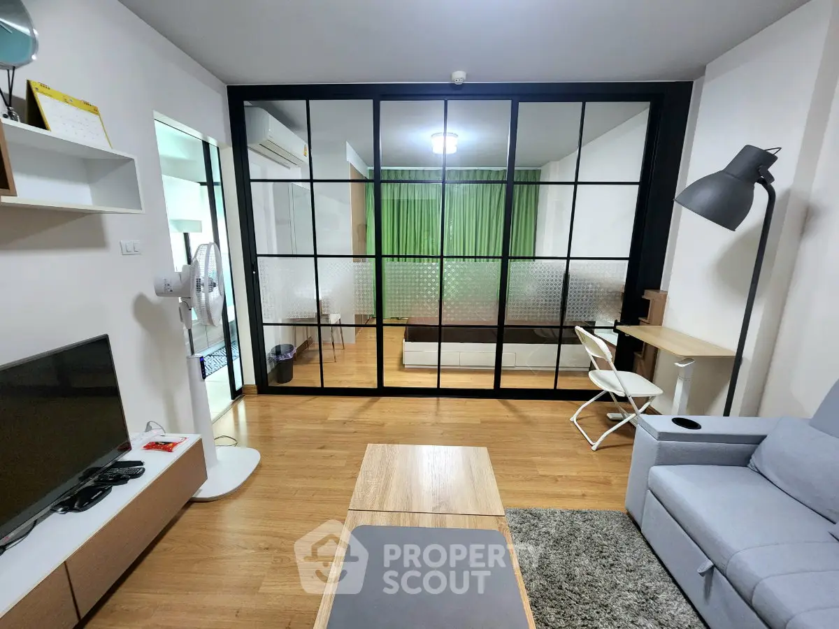 Modern living room with glass partition, cozy seating, and stylish decor in a contemporary apartment.