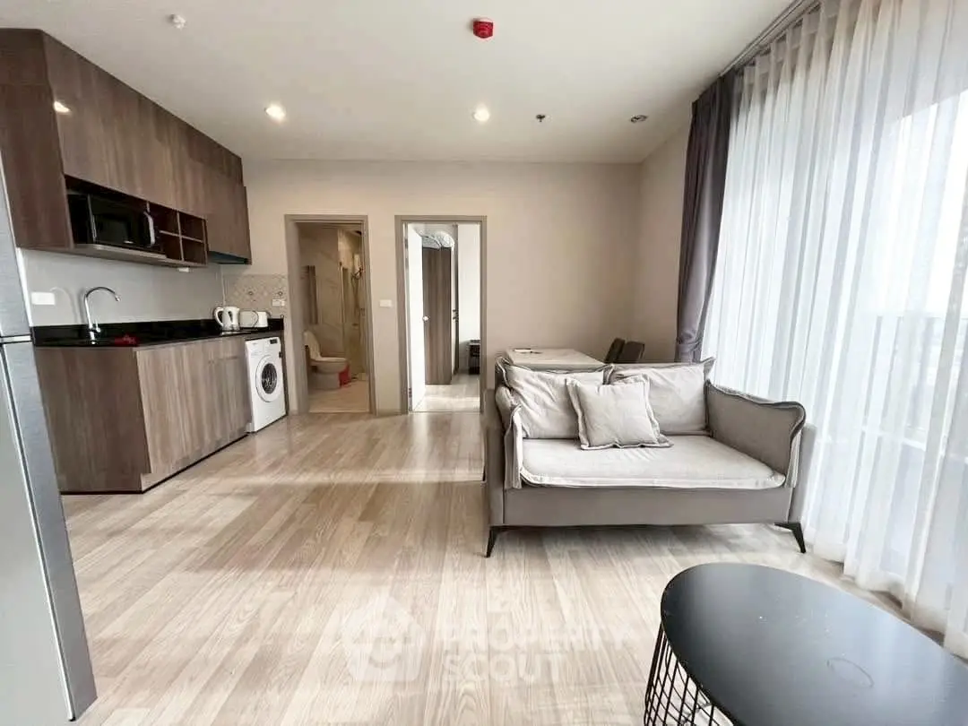 Modern open-plan living room with kitchen and large windows in a stylish apartment.