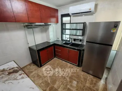 Modern kitchen with sleek cabinetry, stainless steel fridge, and marble countertops.