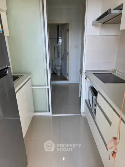 Modern kitchen with sleek appliances and a view into a bathroom