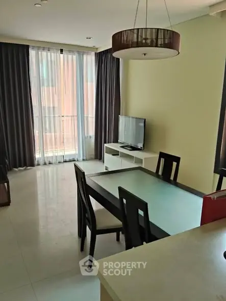 Modern living room with dining area and large window, featuring sleek furniture and natural light.