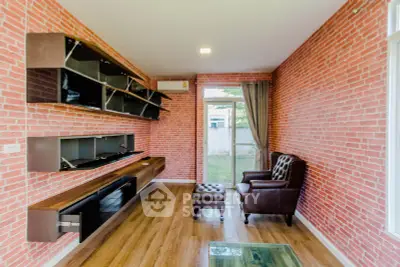 Stylish living room with brick walls and modern furniture, featuring a cozy leather armchair and open shelving.