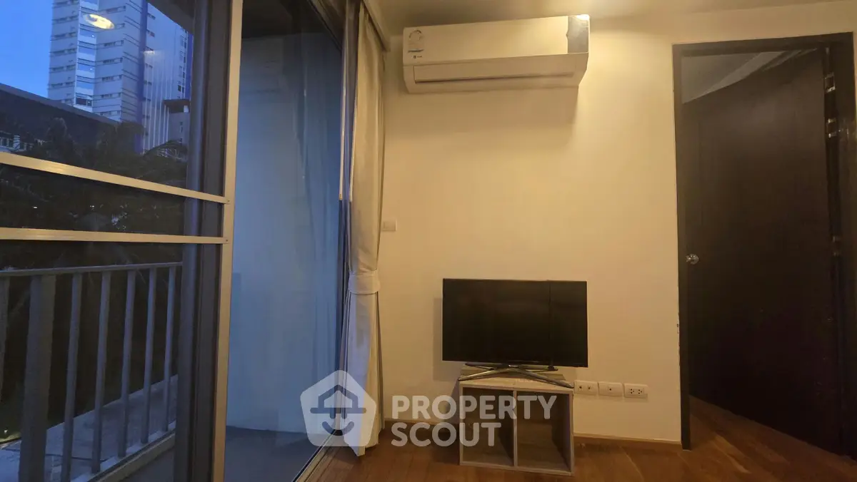 Cozy living room with balcony view and modern air conditioning unit, perfect for urban living.