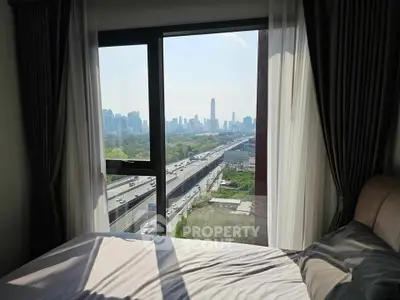 Stunning bedroom view with floor-to-ceiling windows overlooking city skyline and highway.