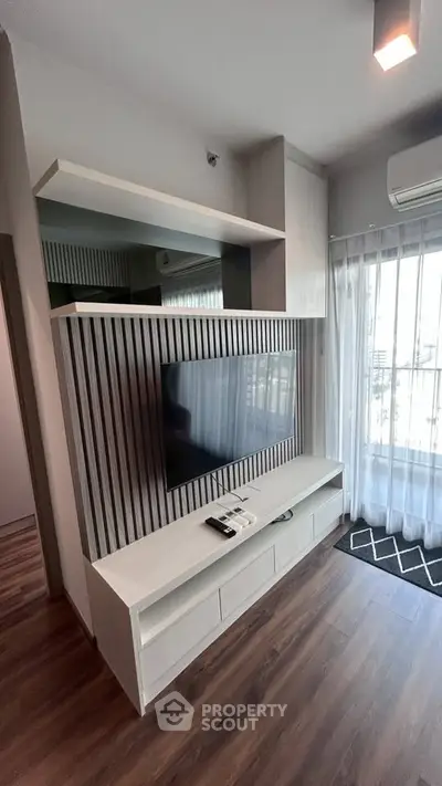 Modern living room with sleek TV unit and large window for natural light.