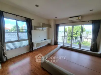 Spacious bedroom with large windows and wooden flooring, offering abundant natural light and serene views.