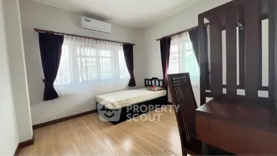 Cozy bedroom with wooden flooring, single bed, and ample natural light from large windows.