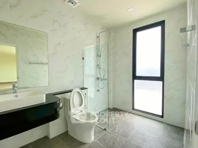 Modern bathroom with glass shower and large window in a stylish apartment.