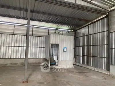 Spacious industrial warehouse with metal walls and small restroom area.