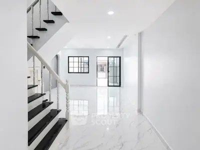 Spacious modern living room with marble flooring and staircase, abundant natural light.