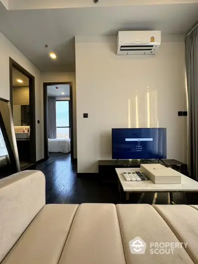 Modern living room with sleek design, featuring a wall-mounted air conditioner and flat-screen TV.