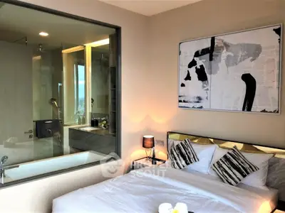 Modern bedroom with stylish decor and glass wall overlooking luxurious bathroom.