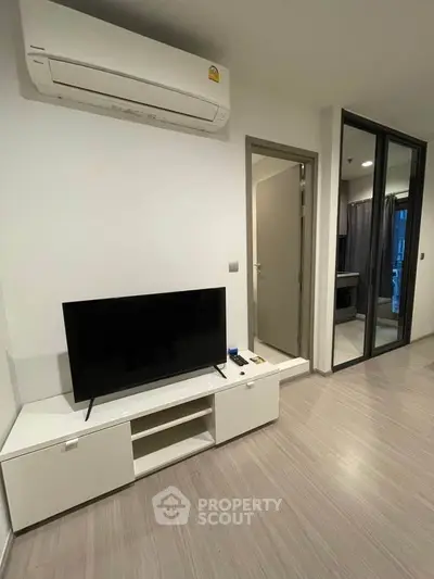 Modern living room with sleek TV setup and air conditioning in a stylish apartment.