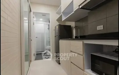 Modern compact kitchen with sleek cabinetry and appliances in a stylish apartment.