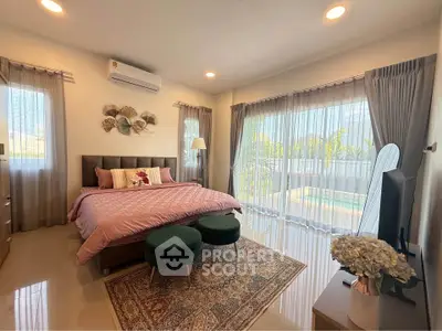 Spacious bedroom with pool view, elegant decor, and natural light