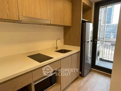Modern kitchen with sleek wooden cabinetry and balcony view