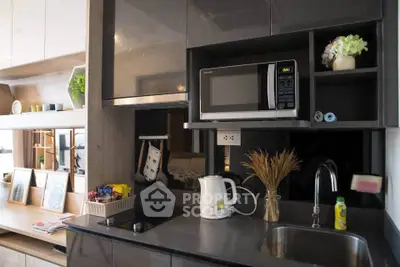 Modern kitchen with sleek cabinetry, microwave, and kettle, perfect for compact living spaces.