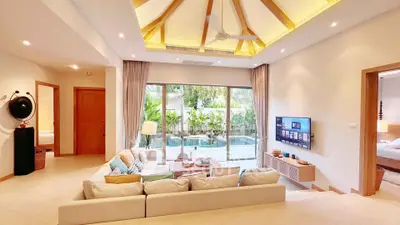 Luxurious living room with pool view, high ceiling, and modern decor in a tropical villa.