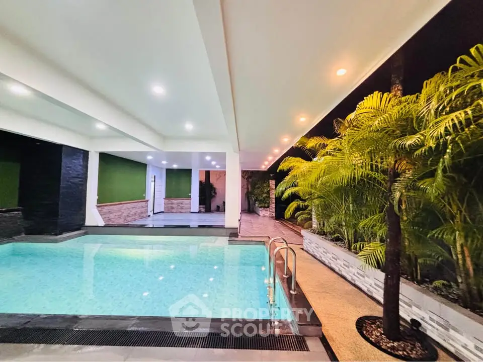 Luxurious indoor pool area with modern lighting and lush greenery, perfect for relaxation and entertainment.