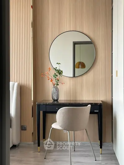 Stylish modern study nook with elegant desk, chair, and round mirror in a cozy apartment.