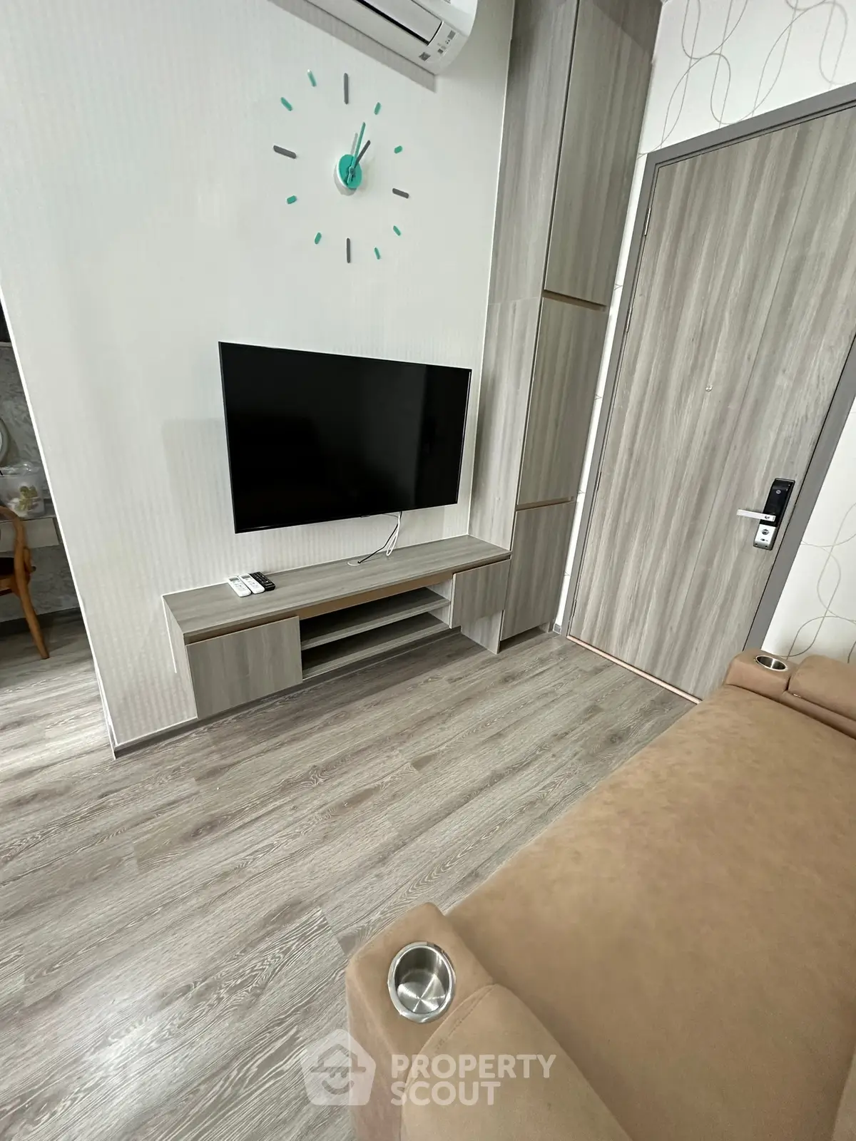 Modern living room with wall-mounted TV and stylish wooden flooring.