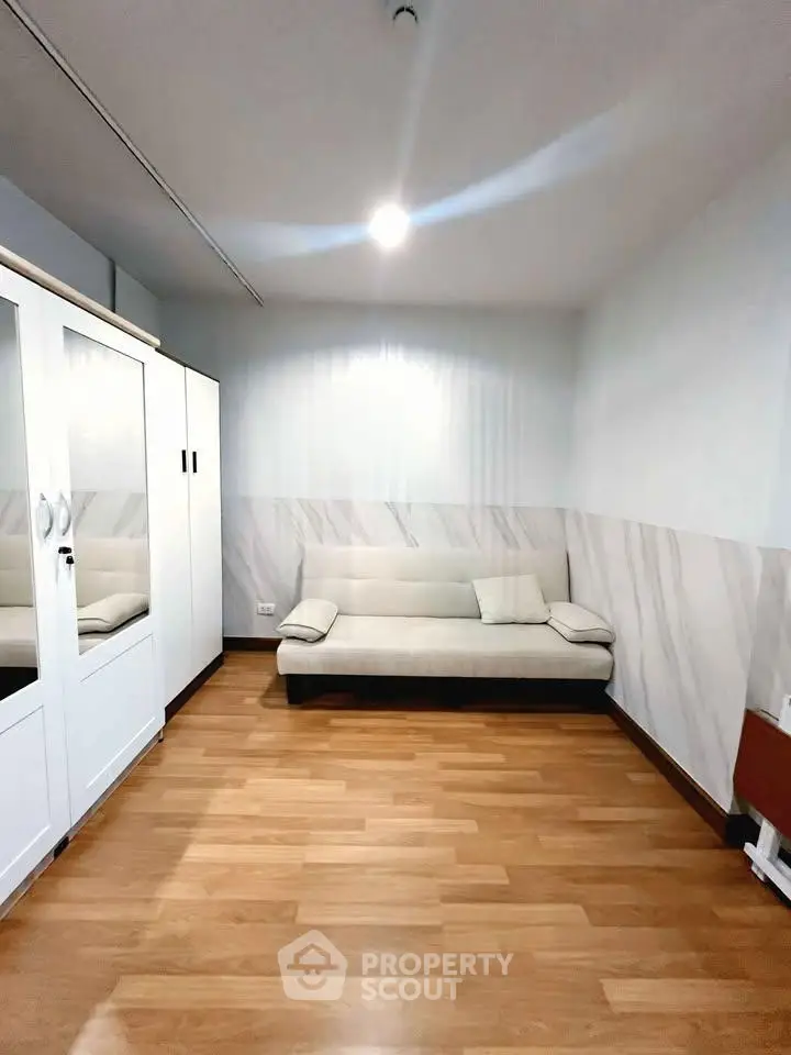 Spacious room with modern sofa and wooden flooring, ideal for cozy living.